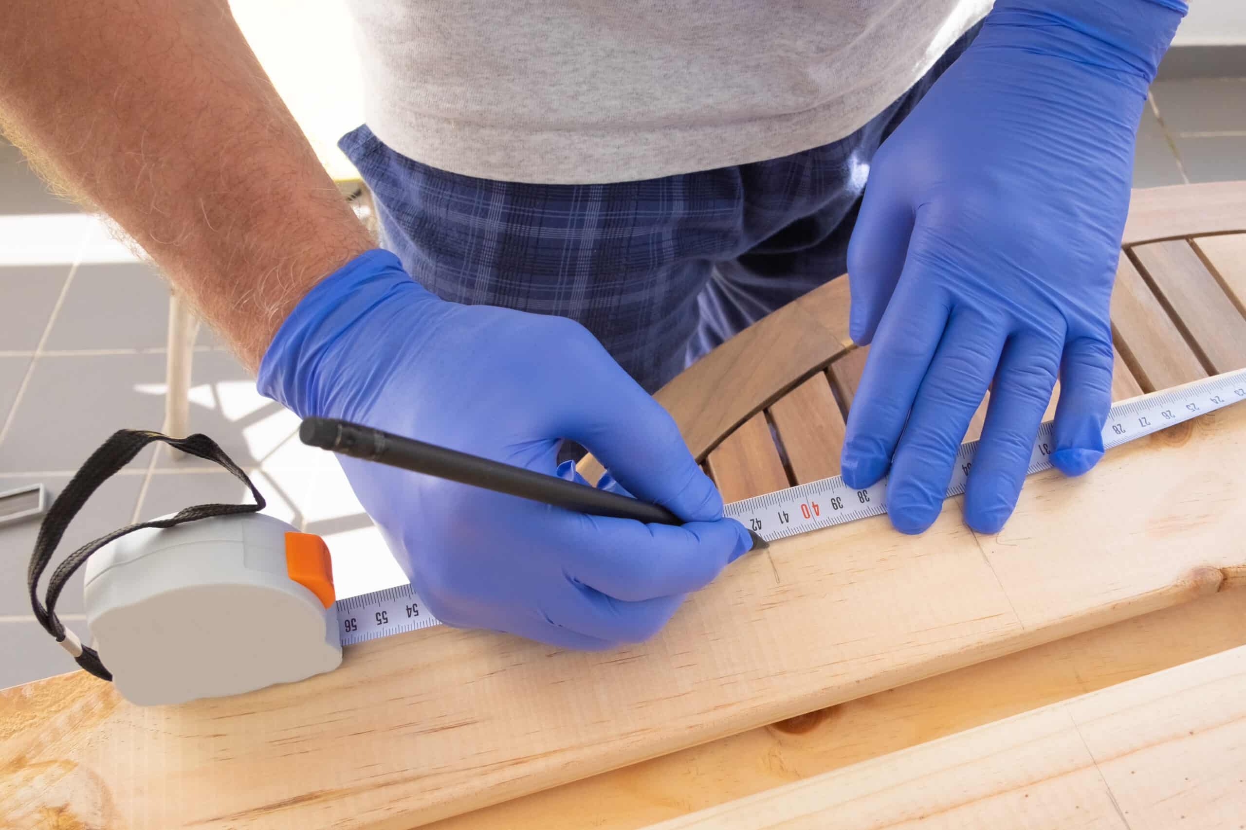 Carpenter marking wooden desk with measuring tape