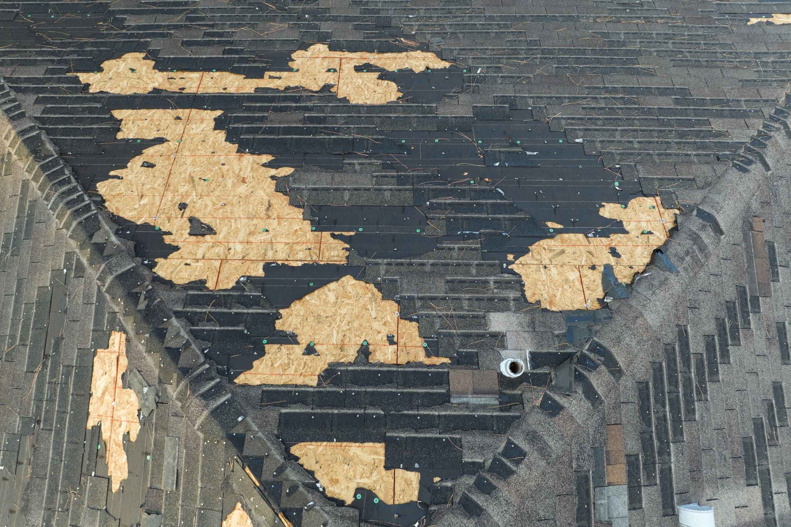 Ruined rooftop in need of repair. Wind damaged house roof with missing asphalt shingles after hurricane Ian in Florida